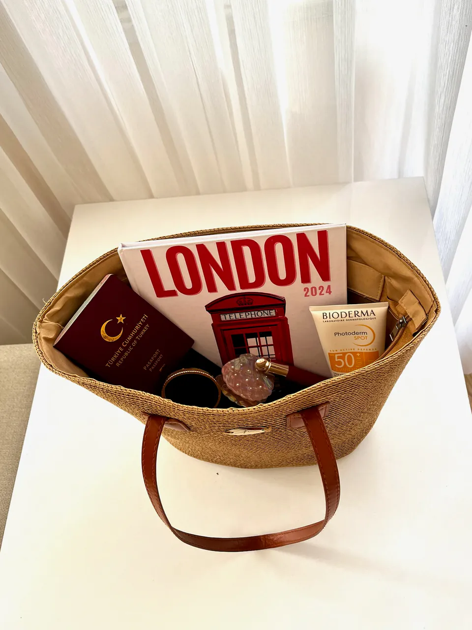 London kapaklı fotokitap, plaj çantasında pasaportla